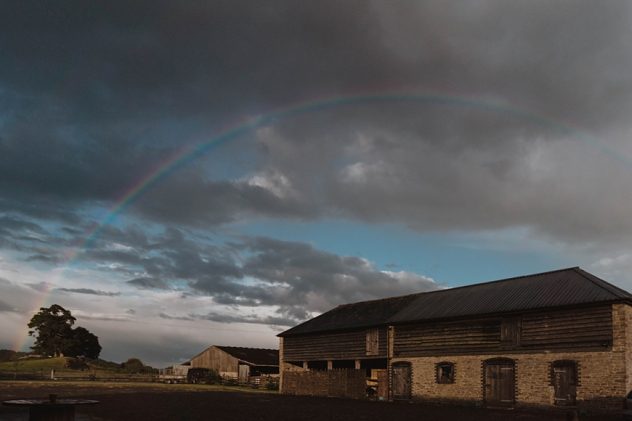 A barn at Wilde Lodge with a rainbow arching over it