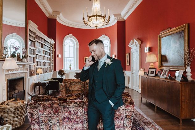 Groom on the phone in the library at Iscoyd Park
