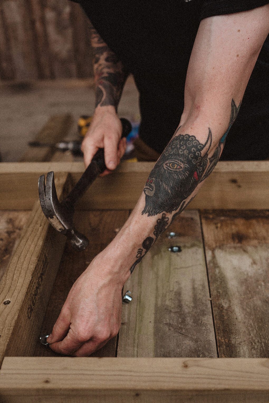 Man with Bison tattoo hammering nails into wood
