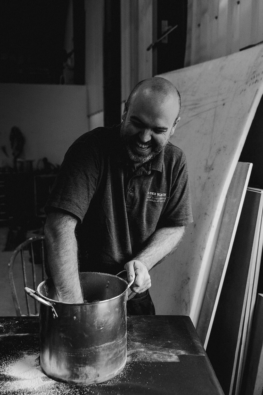 Man with hand in pot mixing gesso whilst smiling