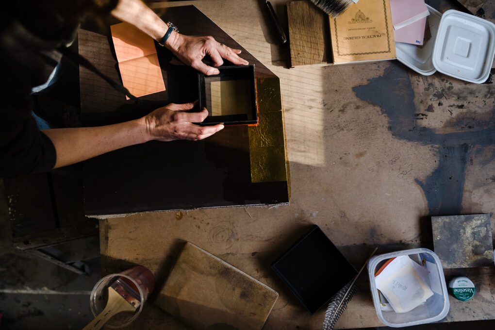 Woman creating leaf gilding on panel