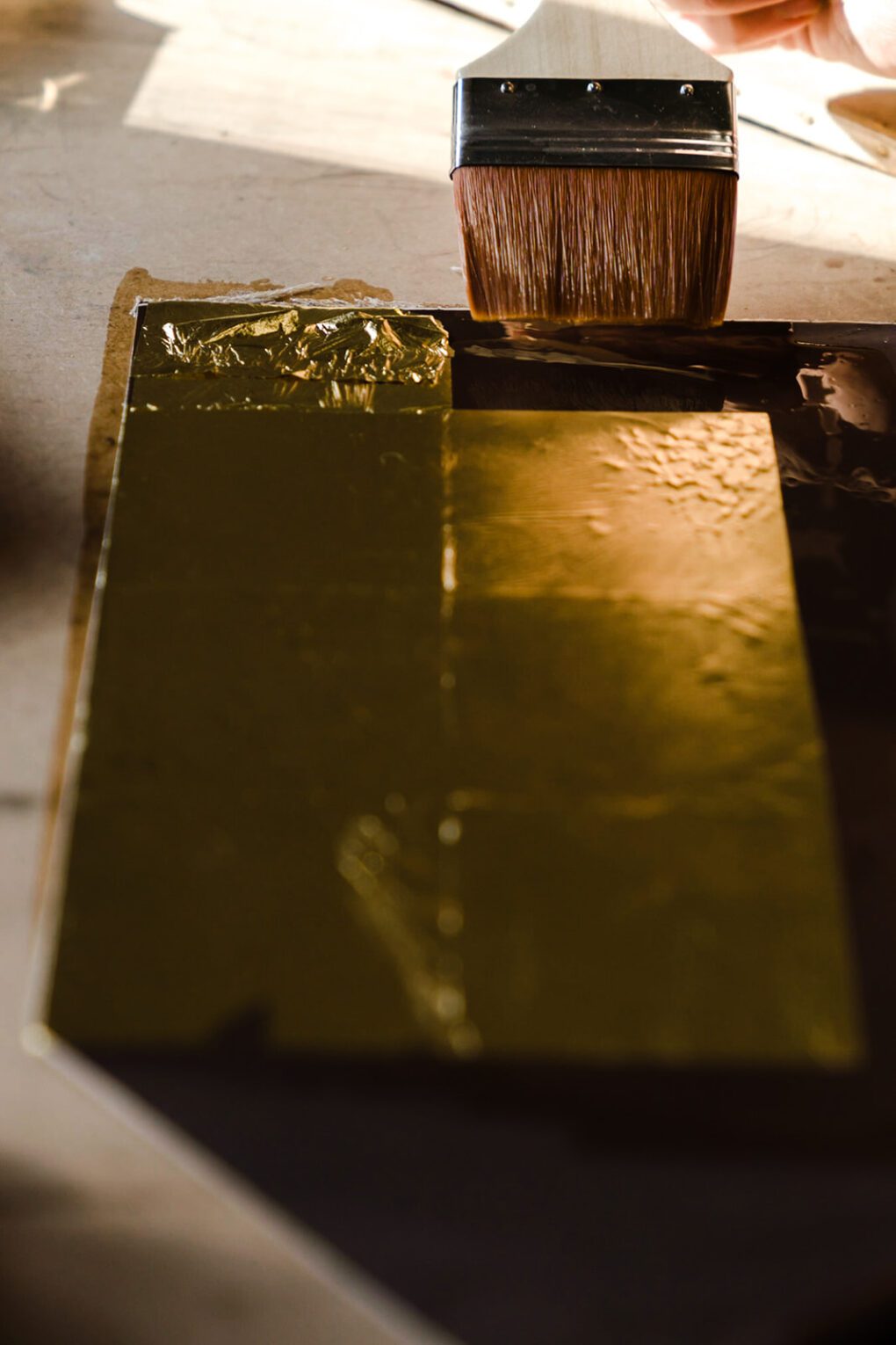Gold leaf being brushed onto glass