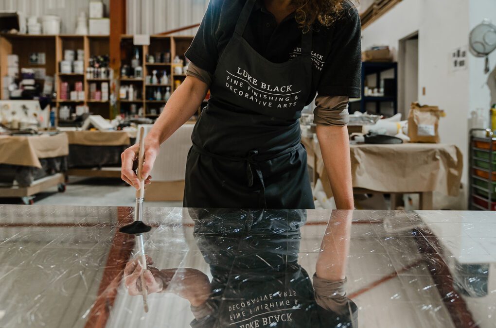 Woman wearing Luke Black apron brushing mirrored surface