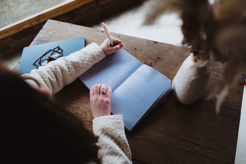 Wedding coordinator writing in diary, business brand storytelling photoshoot