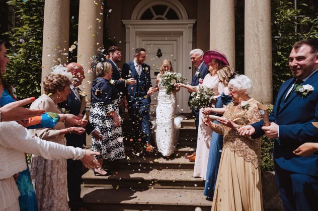 Guests throw confetti at the happy couple outside the front door of Iscoyd Park