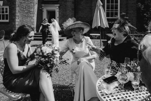 Guests laugh and joke in foreground as bride walks away in the distance at Iscoyd Park wedding