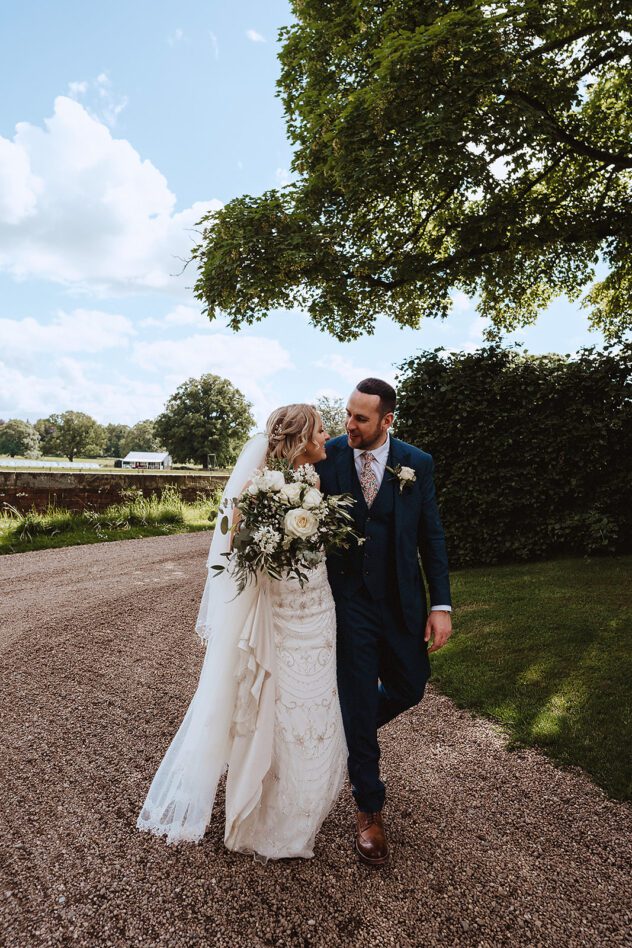 Bride and groom waling and smiling at each other during Iscoyd Park wedding