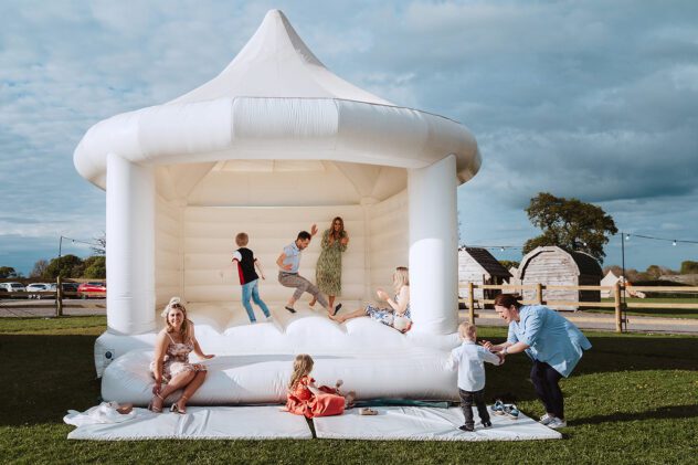 Guests bouncing on white wedding bouncy castle