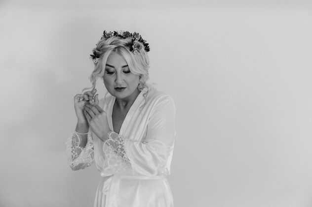 Black and white image of bride fixing her hair whist wearing a white dressing gown