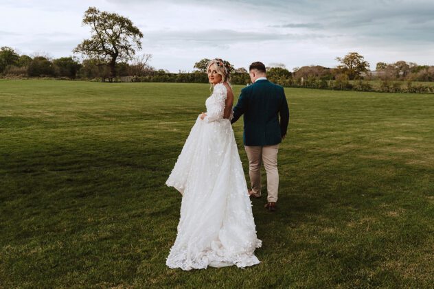 Bride and Groom walking through fields at Stanford Farm