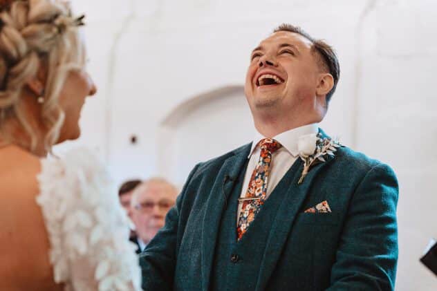 Groom throws head back laughing at Stanford Farm wedding