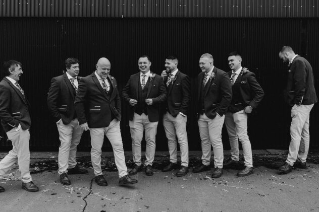 Black and white image of groom stood with groomsmen at Stanford farm wedding