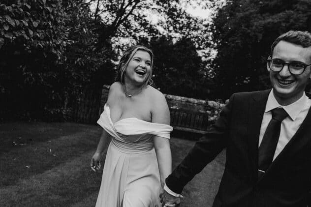 Bride and groom walking and laughing through the grounds of Pimhill barn wedding taken by Shropshire wedding photographer, Indie Love Photography