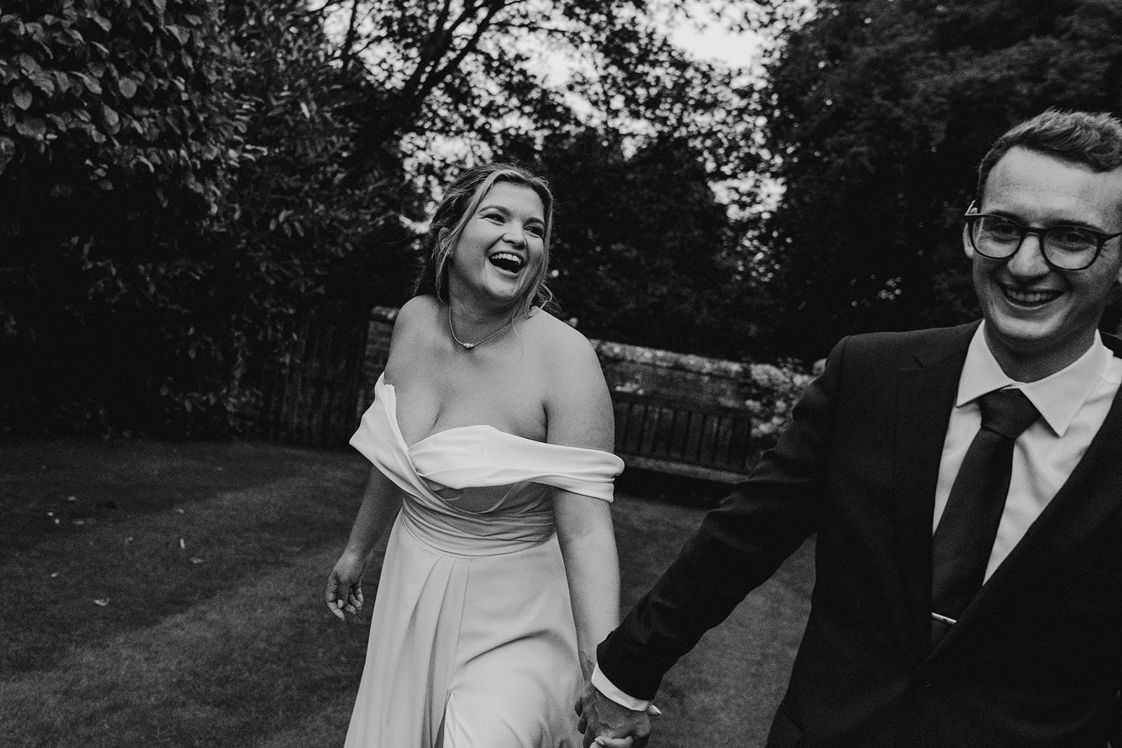 Bride and groom walking and laughing through the grounds of Pimhill barn wedding taken by Shropshire wedding photographer, Indie Love Photography