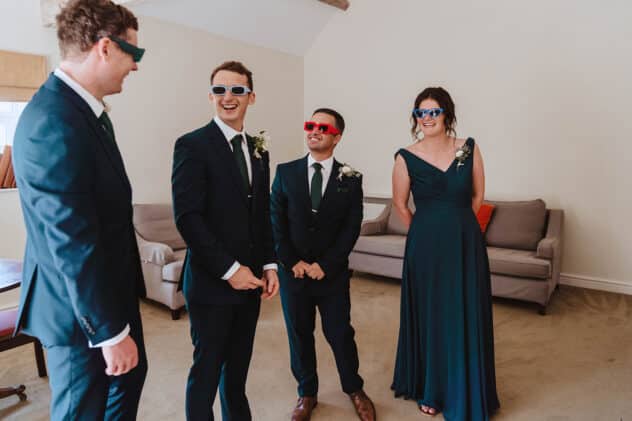 Groomsmen trying on fancy dress sunglasses at Pimhill barn wedding