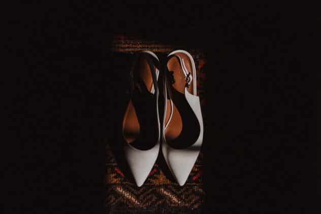 A pair of white sling back shoes on a red rug at Pimhill barn wedding