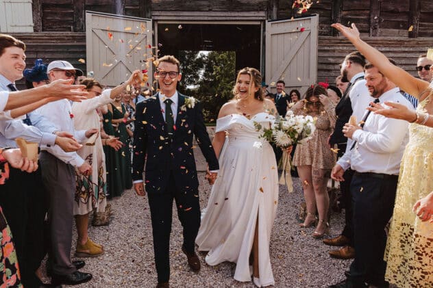 Bride and groom laughing as confetti is thrown at Pimhill barn wedding