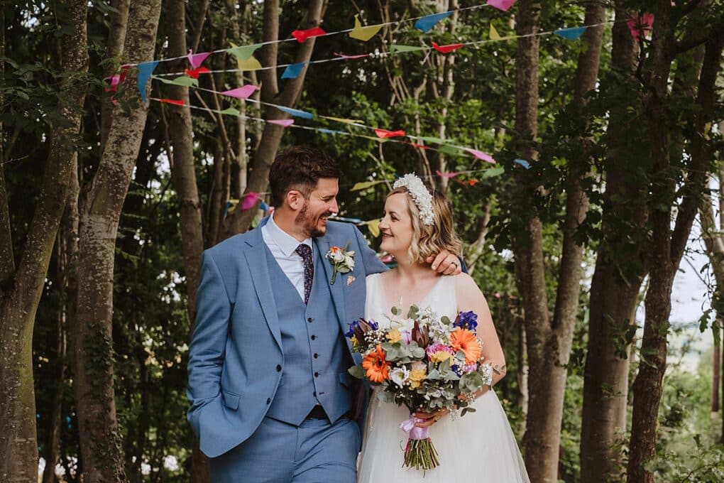 Bride and groom smiling at each other in front of wedding bunting