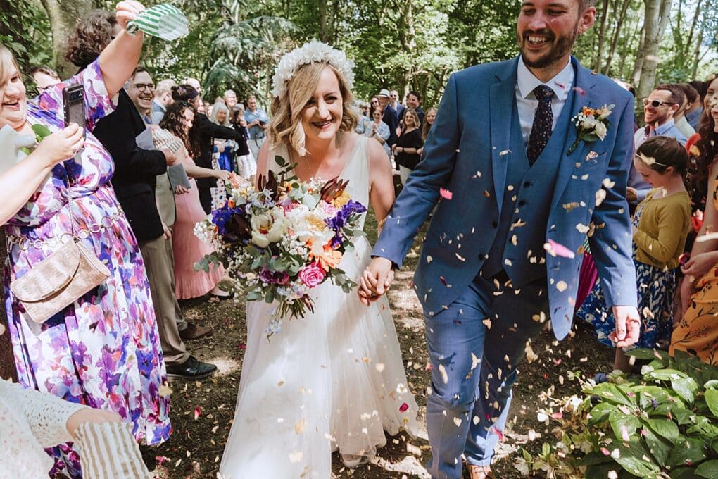 Joyful bride and groom having confetti thrown at them