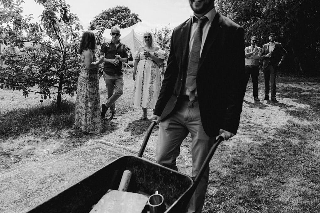 Candid Shropshire wedding photography of wedding guest pushing a wheelbarrow