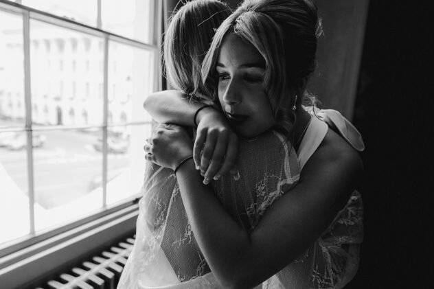 Candid moment of bride and daughter sharing a hug before.