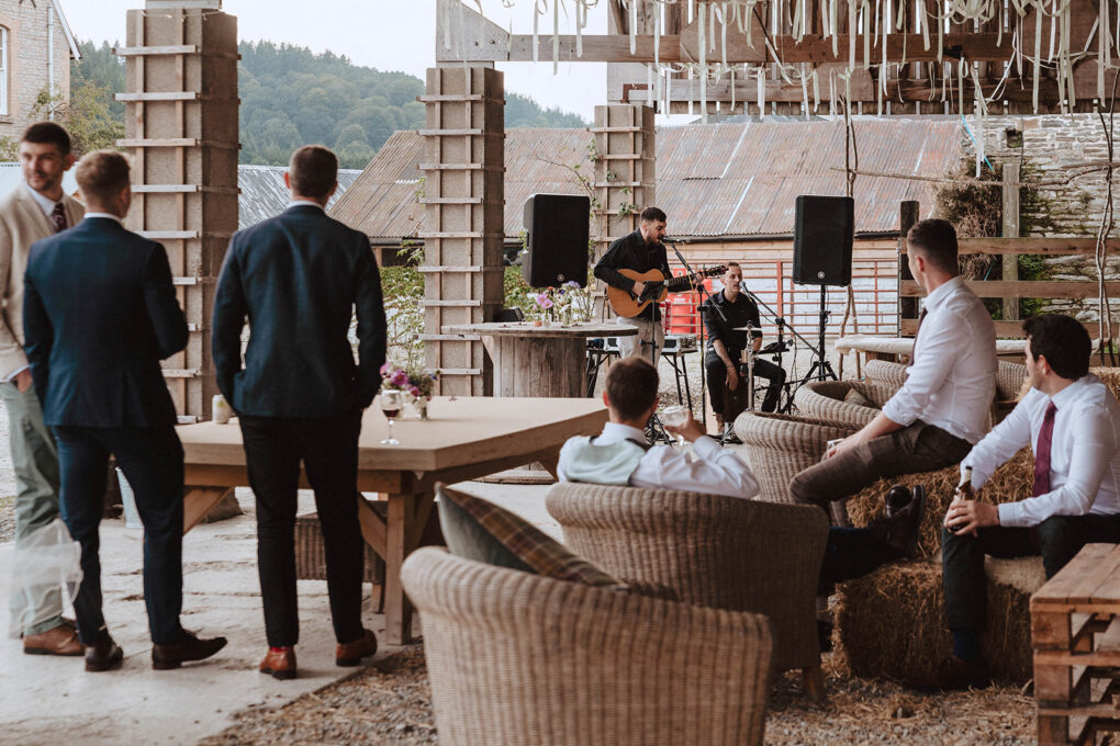 A wide, documentary-style shot of an intimate wedding ceremony at Wilde Lodge, showing the Wilde Lodge outdoor barn on the Shropshire border