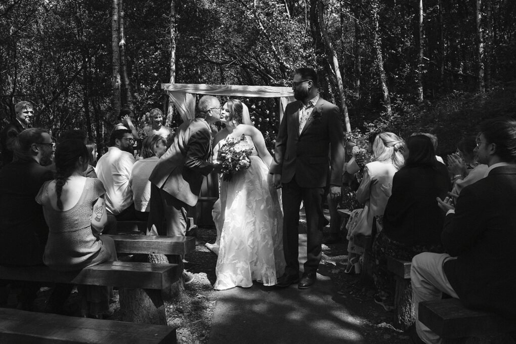 Candid photo of a bride and groom walking down the aisle in the outdoor woodland ceremony area at Glyngynwydd.